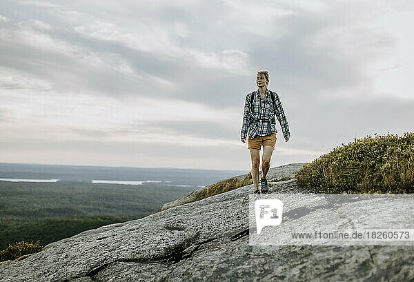 young woman in flannel shirt hikes along Schoodic Mountain  Maine
