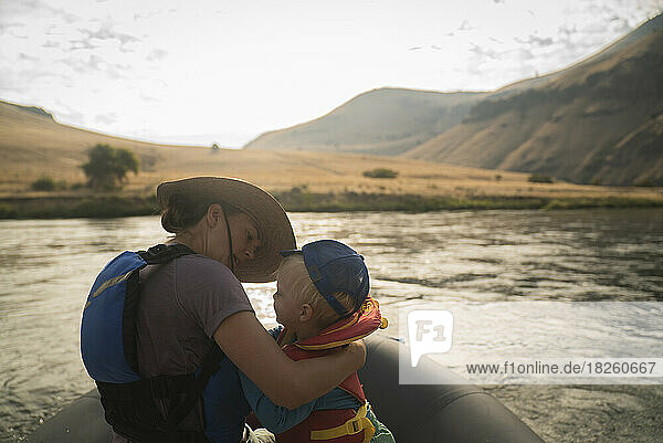 A mom holds a toddler in a raft on a desert river