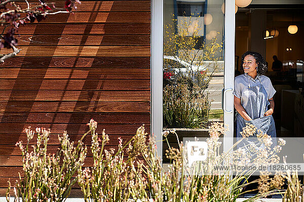 Smiling female owner standing at doorway of coffee shop