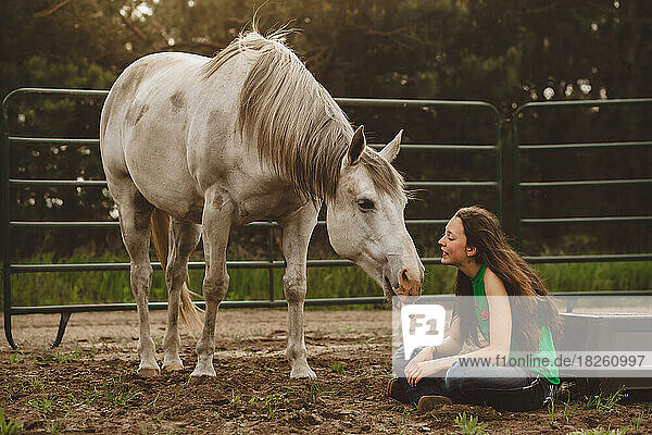 White Horse sticking tongue out with young teen sitting in arena