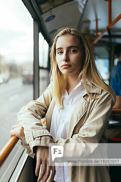 portrait of a woman in a coat and white shirt standing inside the bus