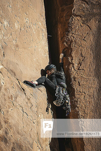 Low angle view of determined woman climbing desert rock
