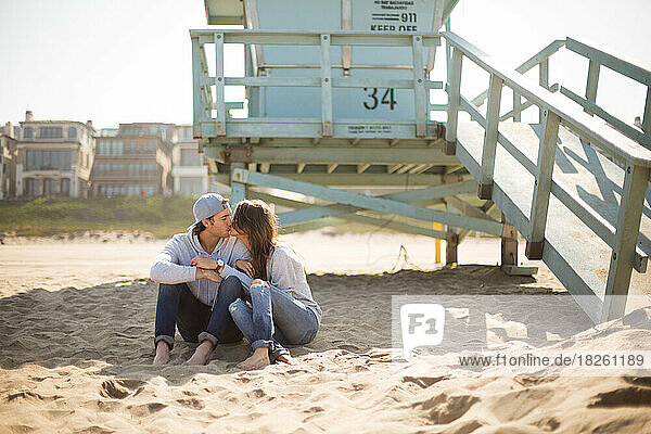 Young couple kissing on a sunny beach in California