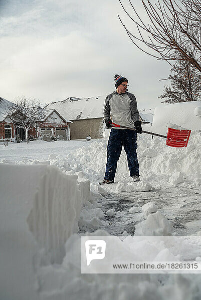 Man shoveling snow off of his driveway after a winter storm.