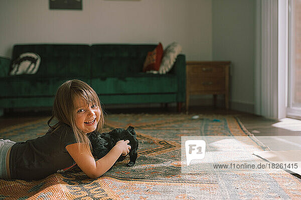 Child playing with black puppy maltese in boho styled room