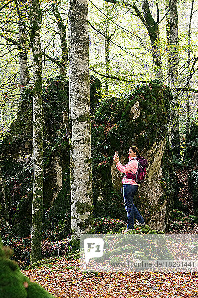 Hiker woman photographing the landscape with smartphone.
