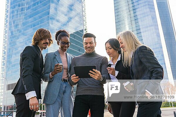Eine Gruppe multiethnischer Geschäftsleute in einem Gewerbegebiet schaut auf ein Tablet