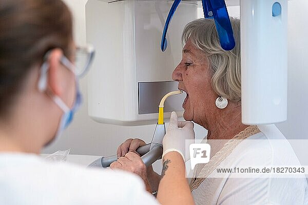 Dental clinic  dental assistant with an elderly woman in the x-ray room  explaining how they have to put the voice