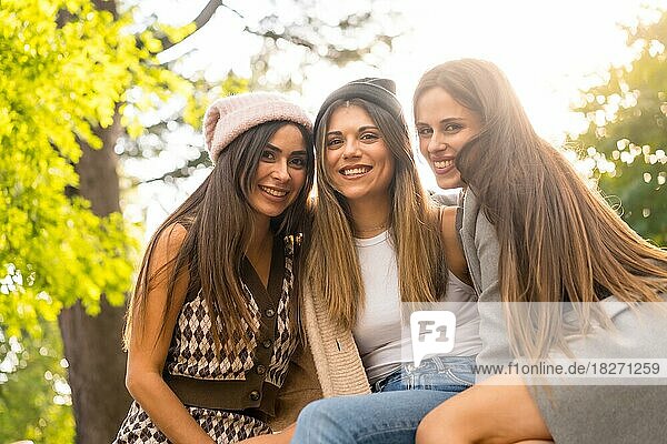 Women friends sitting in a park in autumn  trendy fall lifestyle  carefree  excitement  enjoyment