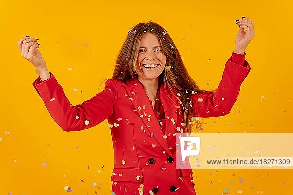 Frau mit Spaß in rotem Kleid auf einem gelben Hintergrund werfen mit Konfetti  Party-Konzept