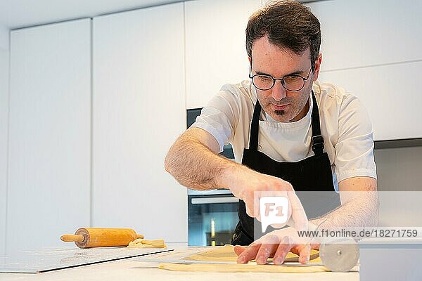 Mann backt hausgemachte Croissants  misst Blätterteig ab und schneidet ihn zu  Arbeit zu Hause