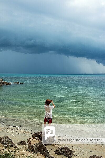 Junger Mann steht am Strand  tropisches Unwetter  Sturm  Gewitter am Strand  Mae Nam Beach  Insel Ko Samui  Thailand  Asien