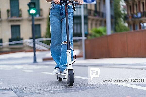 Detail einer jungen brünetten Frau  die sich mit einem Elektroroller in der Stadt bewegt  nachhaltiger Transport