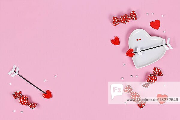 Valentinstag Süßigkeiten  herzförmige Platte und Liebe Pfeile auf rosa Hintergrund mit Kopie Raum