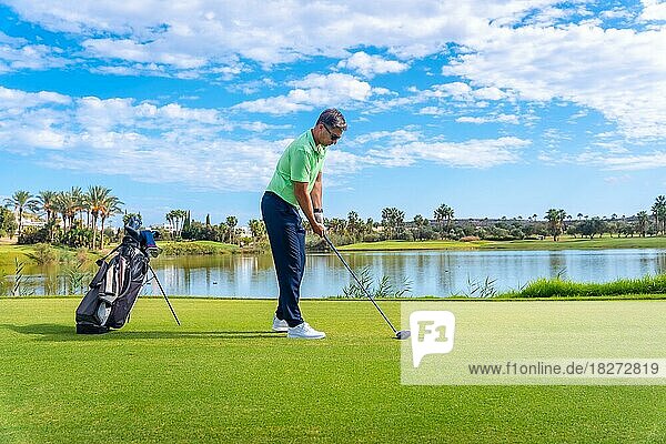 Male golf player on professional golf course. Golfer with driver stick by a lake