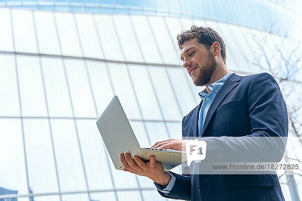 Young businessman or finance man looking at computer outside office  glass building
