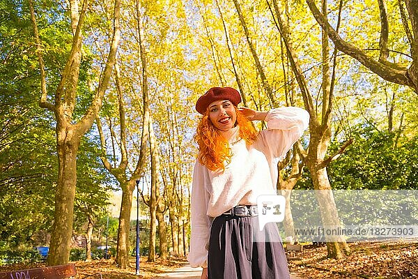Red-haired woman with beret in a park  city forest at sunset  smiling