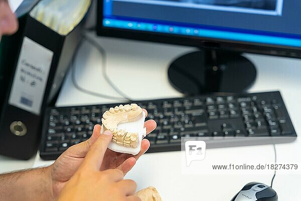 Zahnklinik  Zahnarzt erklärt einem Kunden ausführlich die Zähne  die in ein Modell implantiert werden müssen