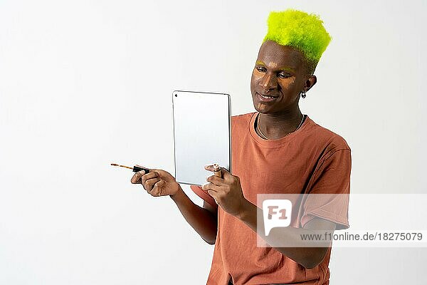 Ein schwuler schwarzer ethnischer Mann  der sich schminkt  LGTBI-Konzept  Porträt  das dunkle Augenringe mit einem Spiegel korrigiert