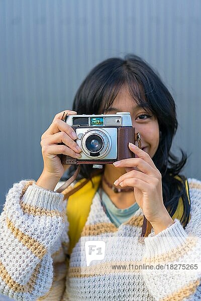 Portrait of a young Asian woman photographing with a vintage photo camera  vacation concept  tourist woman