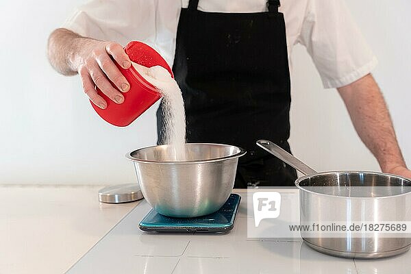 Hands of a man cooking a red velvet cake at home  preparing Swiss meringue with egg whites in a bain-marie  adding sugar  work at home
