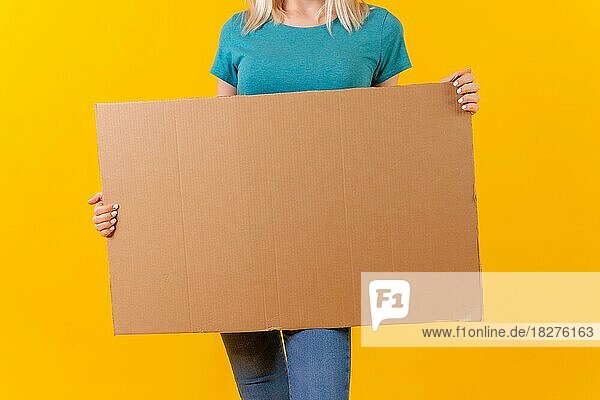 Halten leeren Karton Werbeplakat  blonde kaukasische Mädchen auf gelbem Hintergrund Studio