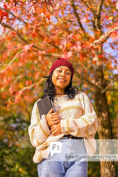 Porträt eines asiatischen Mädchens im Herbst mit einer Tablette lächelnd in einem Wald von roten Blättern  Technologie-Konzept