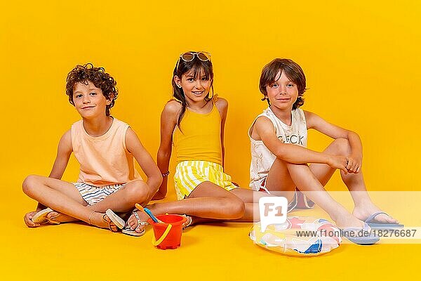 Kinder sitzen auf dem Boden und genießen die Feiertage mit Spielzeug  gelber Hintergrund