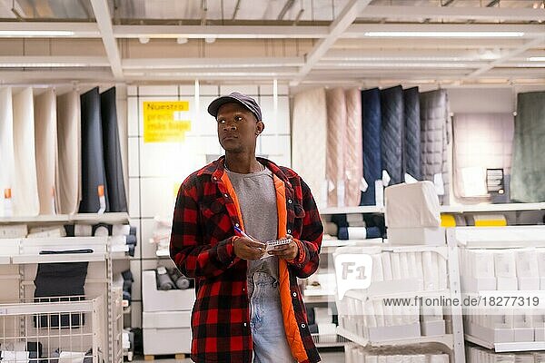 Black ethnic man shopping in a supermarket for carpets and towels