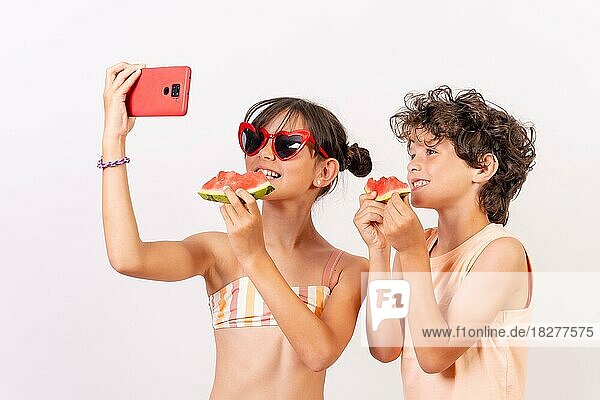 Kinder genießen den Sommer  essen eine Wassermelone und machen ein Selfie mit dem Handy. Weißer Hintergrund