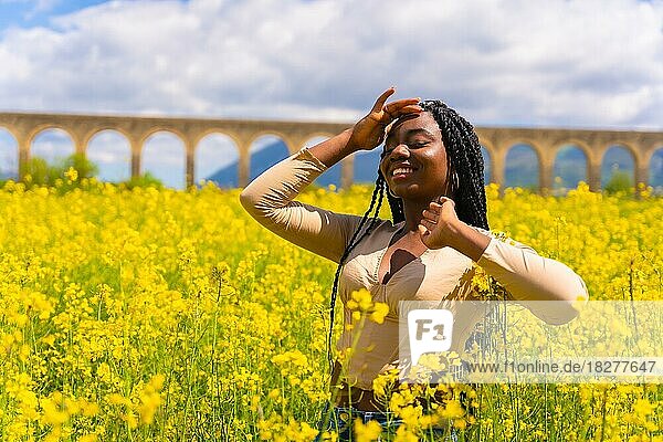 Lifestyle  portrait of a black ethnic girl with braids  in a field of yellow flowers