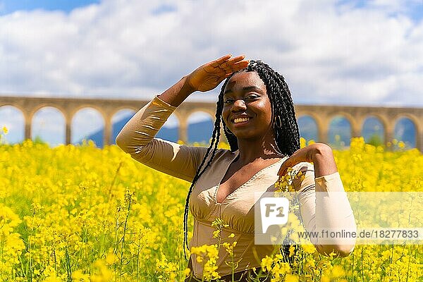 Lebensstil  Porträt eines schwarzen ethnischen Mädchens mit Zöpfen  in einem Feld mit gelben Blumen