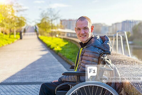 Portrait of a disabled person in a wheelchair by a river in the city sunset