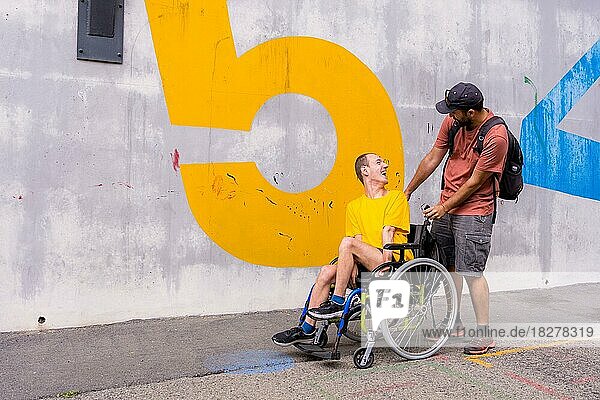 Behinderte Person im Rollstuhl mit einer Zementwand  die sich mit einem Freund amüsiert
