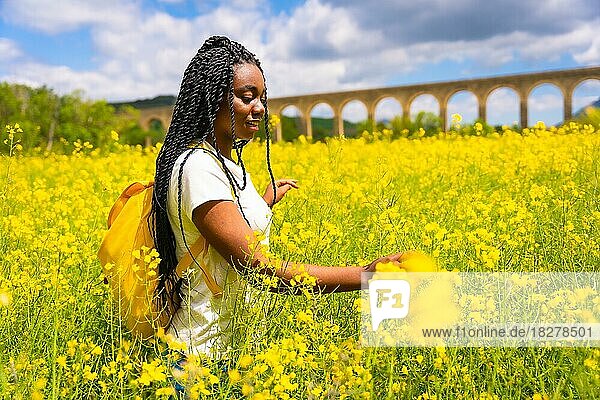 Eine Reisende schwarz ethnischen Mädchen mit Zöpfen in einem Feld von gelben Blumen