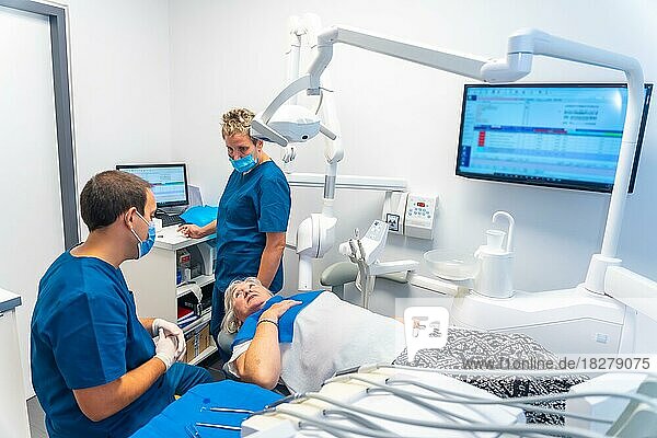 Zahnklinik  Zahnarzt und Assistentin erläutern einer älteren Frau die zahnärztliche Untersuchung