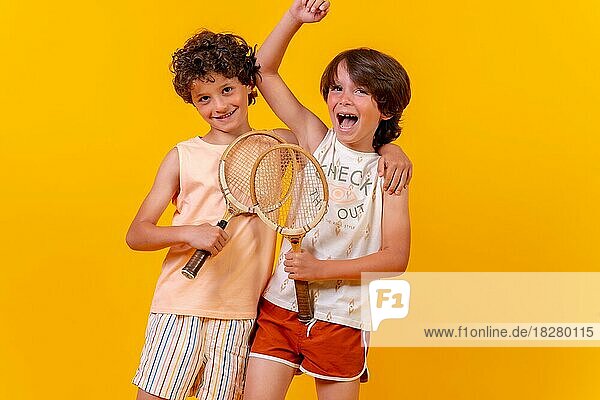 Porträt von zwei Brüdern  die im Sommerurlaub Tennis spielen und Spaß haben  gelber Hintergrund