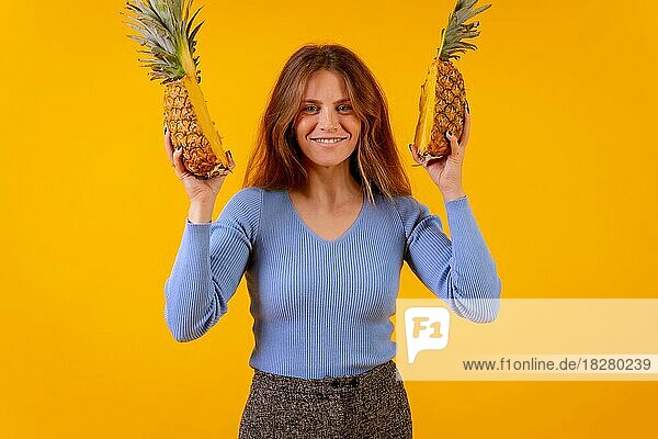 Frau mit Ananas in Sonnenbrille  lächelnd mit halbierter Ananas  gelber Hintergrund