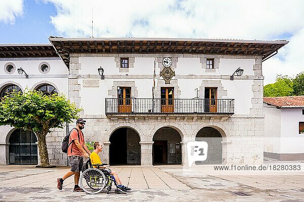 A disabled person in a wheelchair walking through the town square having fun with a friend