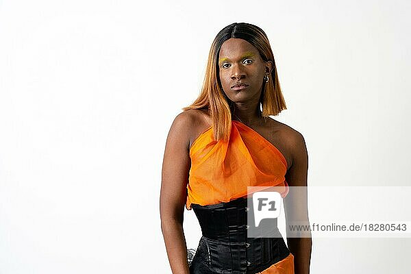 Schwarzer ethnischer Mann im Studio mit weißem Hintergrund  LGTBI-Konzept  trägt ein orangefarbenes Kleid