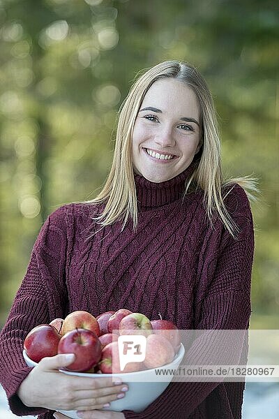 Porträt einer jungen blonden Frau  hält eine Schale mit Äpfeln  Oberbayern  Bayern  Deutschland  Europa