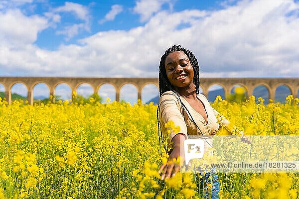 Lebensstil  Genießen der Natur in Freiheit  Porträt eines schwarzen ethnischen Mädchens mit Zöpfen  in einem Feld mit gelben Blumen
