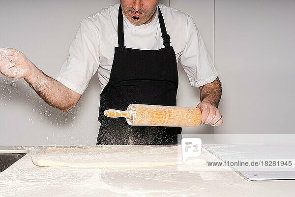 Mann backt hausgemachte Croissants  bereitet den Blätterteig vor  gibt Mehl dazu und drückt ihn flach