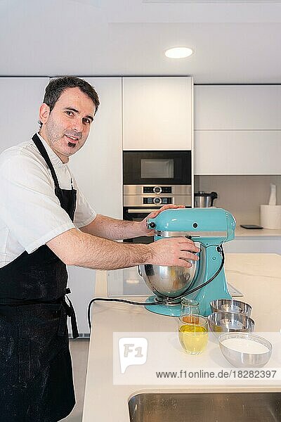 A man baker bakes a red velvet cake at home  preparing the cake in the kitchen robot  work at home