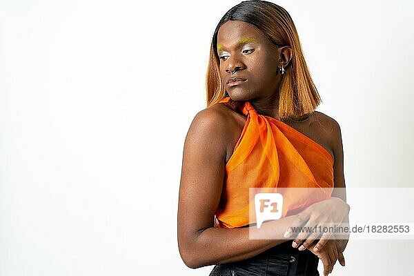Black ethnic man in a studio  LGTBI concept  portrait wearing an orange and black dress and with a wig