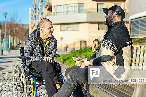 Ein behinderter Mensch im Rollstuhl mit einem Freund  der sich amüsiert  Normalität für Behinderte