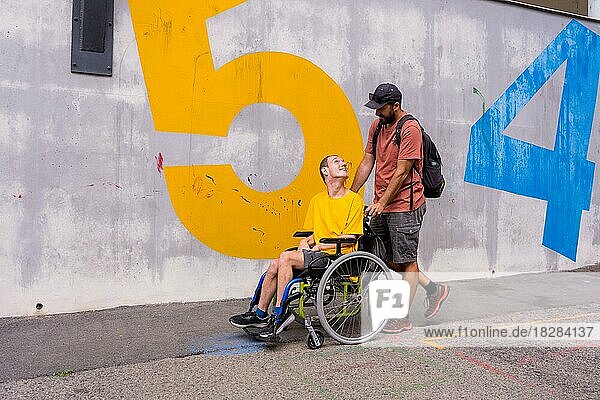 Behinderte Person im Rollstuhl mit einer Zementwand  die sich mit einem Freund amüsiert