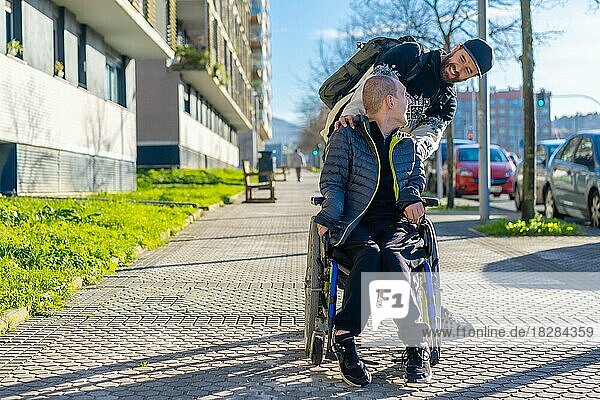 Eine behinderte Person im Rollstuhl geht im Winter mit einem Freund im Rollstuhl auf der Straße spazieren