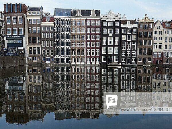 Reihe typischer Häuser mit Reflexion im Damrak  Kanalwasser  Amsterdam  Noord-Holland  Holland  Niederlande  Europa
