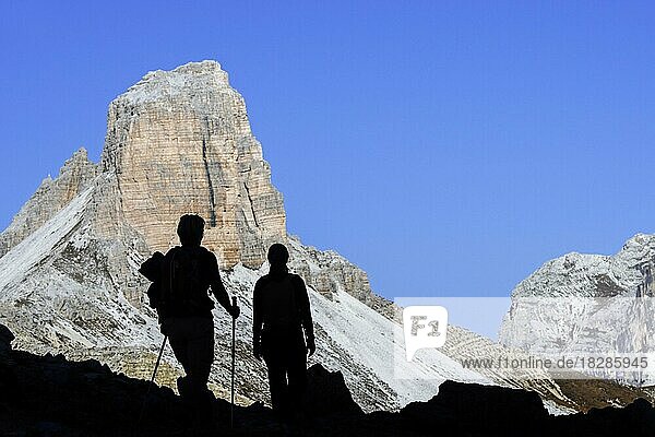 Zwei Bergwanderer vor der Silhouette des Torre dei Scarperi  Schwabenalpenkopf  Sextner Dolomiten  Parco Naturale Tre Cime  Südtirol  Italien  Europa